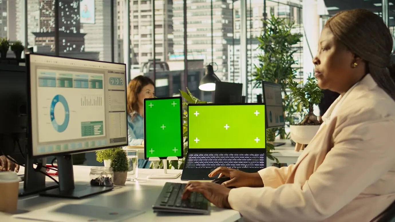 Dispositivos con pantalla aislados en un escritorio de oficina junto a un empleado que edita documentos