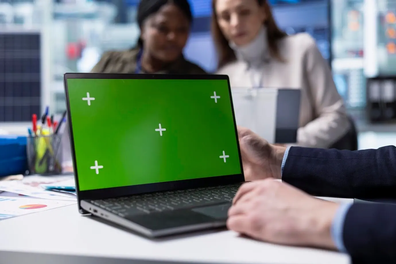 Un operario de fábrica usa un portátil de maqueta junto a ejecutivos que debaten estrategias.