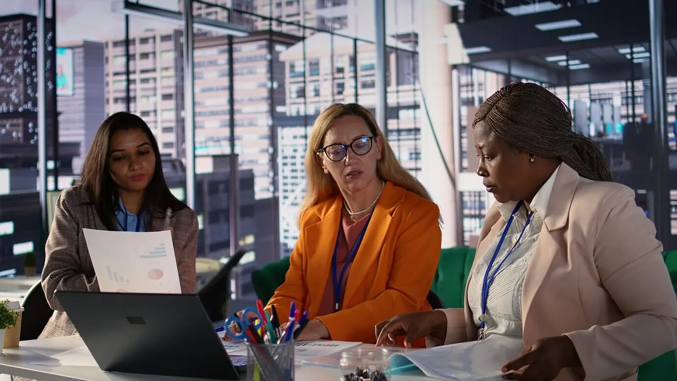 Mujeres ejecutivas ambiciosas colaborando en un entorno laboral diverso.